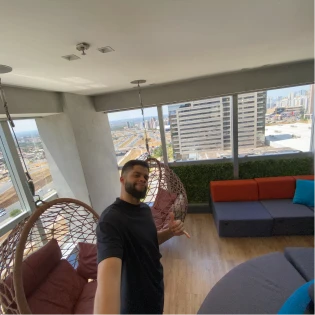 Igor Souza at a rooftop lounge with a city view